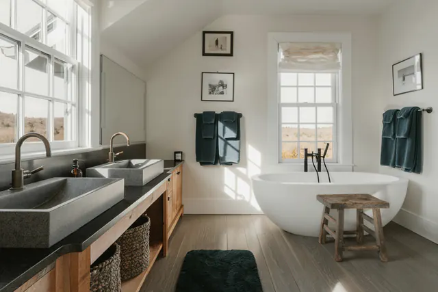 Een lichte badkamer met twee wastafels en een vrijstaand bad