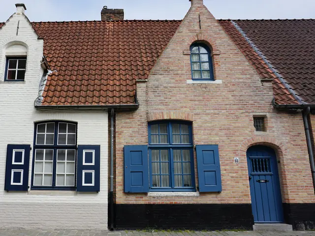Twee oude huisjes naast elkaar in Brugge, een wit en een bakstenen, met blauwe luiken en deuren