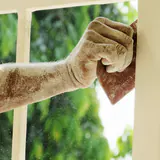 Een arm vol stof tegen een wit houten raam