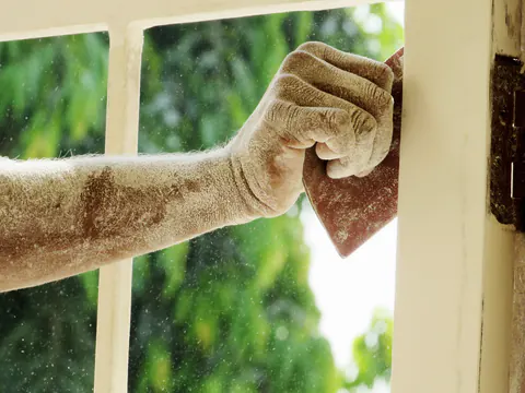 Een arm vol stof tegen een wit houten raam