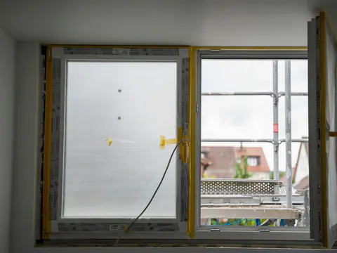 Een nieuw raam nog in de beschermfolie, met een stelling buiten