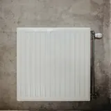 Een witte radiator aan een grijze betonnen muur