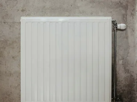 Een witte radiator aan een grijze betonnen muur