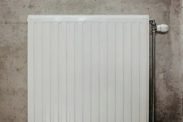 Een witte radiator aan een grijze betonnen muur