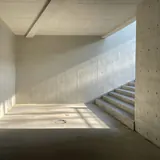 Een lege ruimte met betonnen muren en een trap, in het zonlicht