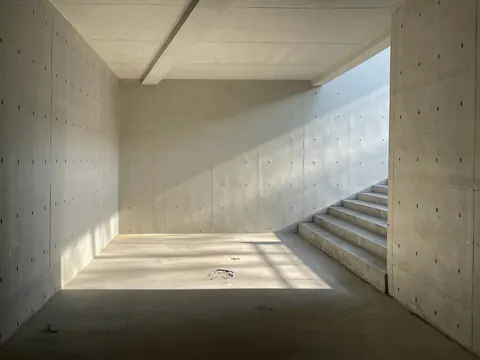 Een lege ruimte met betonnen muren en een trap, in het zonlicht