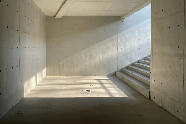 Een lege ruimte met betonnen muren en een trap, in het zonlicht