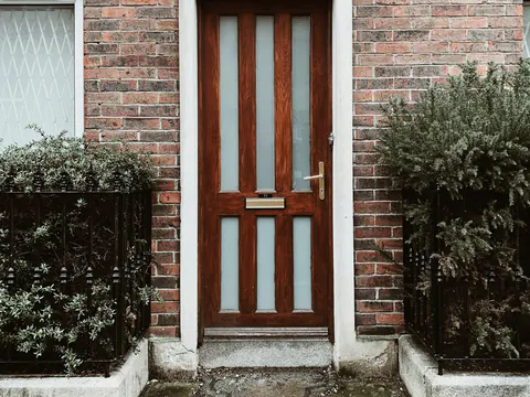 Een houten voordeur onder een boog in een bakstenen gevel