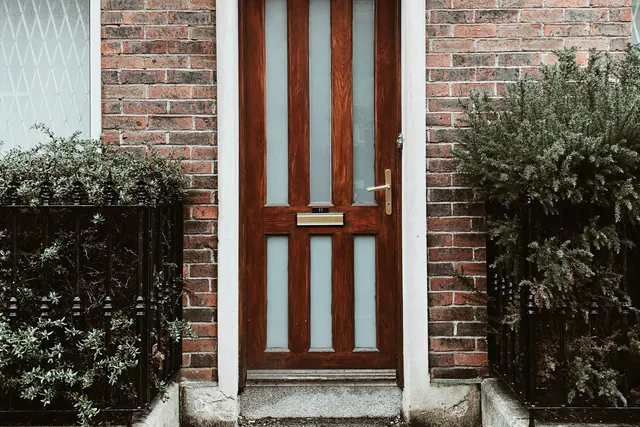 Een houten voordeur onder een boog in een bakstenen gevel