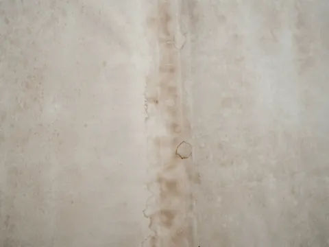 Een witte muur met een bruine streep van doorgelopen water