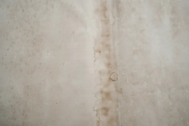 Een witte muur met een bruine streep van doorgelopen water
