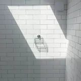 Een witte betegelde douche met een lichtbundel van een dakraam