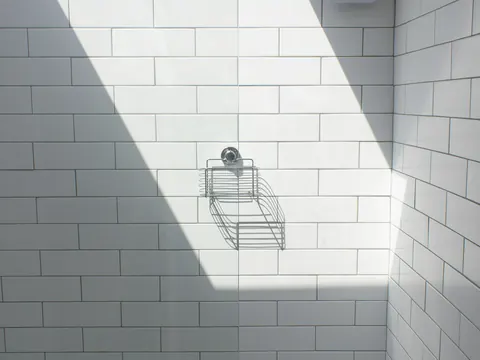 Een witte betegelde douche met een lichtbundel van een dakraam