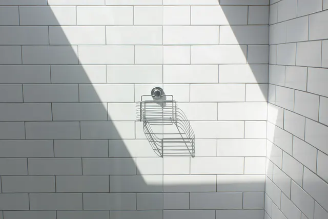 Een witte betegelde douche met een lichtbundel van een dakraam
